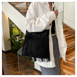 Detail view of bohemian black fringe shoulder bag with silver metal eyelets and suede texture