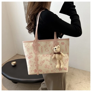 Elegante borsa tote crema con graffiti rosa e ciondolo a orsetto su una modella