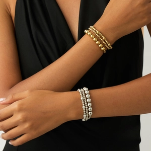 Close-up of layered gold and silver beaded bracelets set worn on female wrist