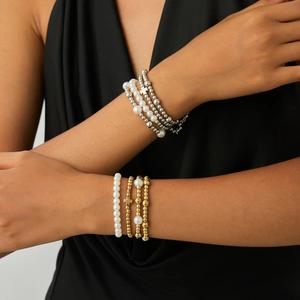 Layered faux pearl and CCB bead bracelet set with cross charms on a model's wrist