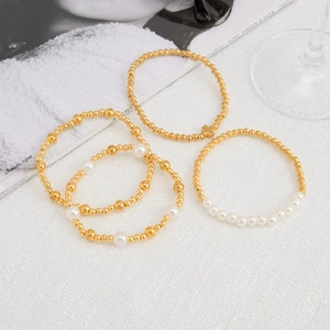 Detailed macro view of a 4-piece gold beaded bracelet set with faux pearls and cross charm