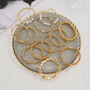 Close-up of golden beaded bracelets and faux pearl strand set in glass tray
