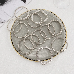 Detail of beaded bracelet set with faux pearls and silver beads on glass tray