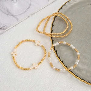 Detail of four-piece beaded bracelet set with faux pearls and gold beads on a tray