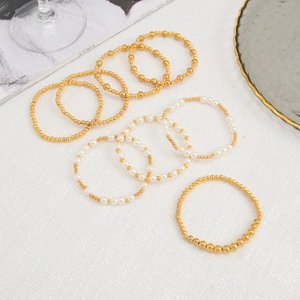 Detail of layered gold beaded bracelet set with white pearls on a Vogue magazine background