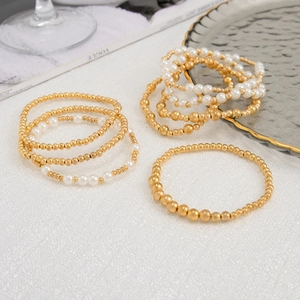 Detail of layered gold metal beads and white pearls bracelet set on a fashion magazine