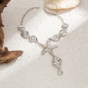 Dettaglio di una collana marina in argento con ciondoli a stella marina e conchiglie sulla sabbia