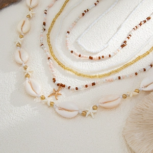 Detalle de cadena corporal multicapa estilo océano con colgantes de estrella y concha