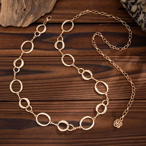 Detail of gold metal waist chain with hammered texture links and a rose pendant charm