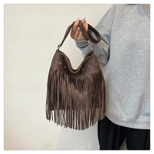 Close-up of bohemian dark coffee suede shoulder bag featuring long fringe and metal eyelets