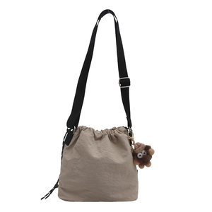 Fashionable khaki drawstring bucket bag with black strap and brown plush toy charm