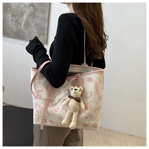 Detailed side view of tote bag with graffiti prints and cute plush bear charm