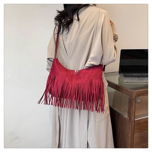 Détail d'un sac à bandoulière en daim bordeaux avec de longues franges et double zip