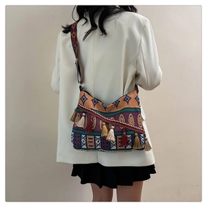Detail of colorful ethnic woven crossbody bag featuring bohemian tassels and wide strap
