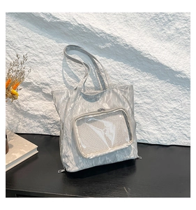 Close-up of metallic silver tote bag with pleated texture and mesh zipper pocket detail