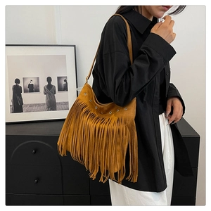 Dettaglio borsa a tracolla boho con frange, occhielli metallici e texture in pelle