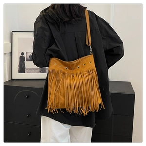 Dettaglio borsa scamosciata marrone con frange lunghe e occhielli metallici su modella