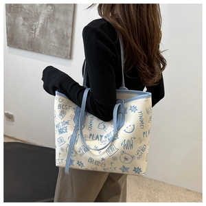 Dettaglio della grande borsa tote con stampe graffiti blu e manici in pelle azzurro cielo