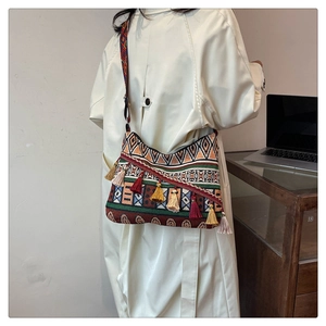 Detailed side view of ethnic crossbody bag with jacquard patterns and colorful tassels