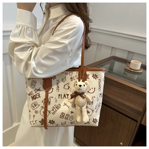 Detail of graffiti print tote bag with brown straps and cute teddy bear charm pendant