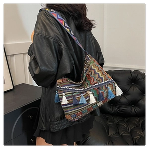 Close-up of ethnic geometric woven shoulder bag with colorful tassels and wide embroidered strap
