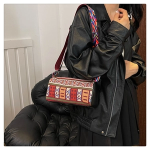 Détails de motifs ethniques tissés et bandoulière large sur un sac cylindrique noir chic