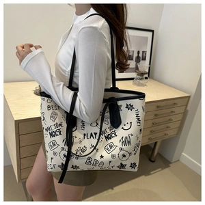 Dettaglio di una grande borsa tote crema con stampe graffiti nere e spalline robuste