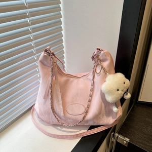 Sac hobo rose avec bandoulière chaîne et breloque nuage dans un décor de fenêtre