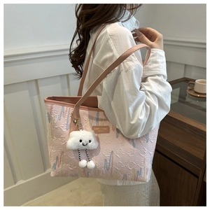 Detalle del bolso tote rosa grabado con costuras de colores y colgante de peluche
