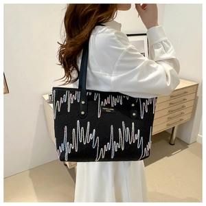 Detail of black tote bag featuring colorful zigzag stitching and gold metal rivets