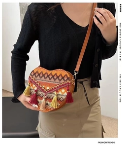 Detalle del bolso bandolera tejido en forma de corazón con motivos étnicos y borlas