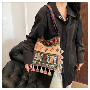 Detailed shot of ethnic woven tote bag with colorful tassels and wide patterned shoulder strap