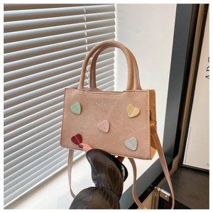 Detail view of pink suede bag featuring colorful heart patches and fashion lettering