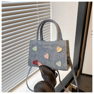 Close-up of grey casual handbag with colorful heart patches and fashion text logo