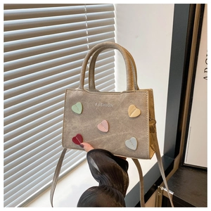 Detail of canvas handbag featuring five colorful 3D leather heart patches and fashion print