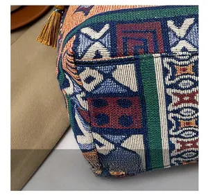 Detailed macro view of ethnic jacquard weave patterns and fringe tassels on a handbag