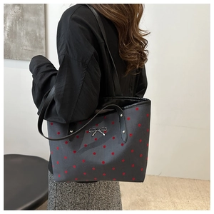 Détail du grand sac cabas en toile à pois rouges avec nœud métallique porté à l'épaule