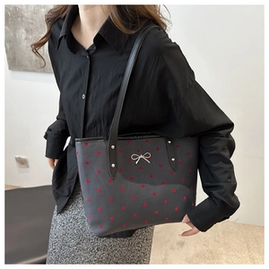Détail du nœud en métal argenté sur un sac fourre-tout à motifs de pois rouges