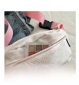 Détail du sac banane blanc texturé montrant la poche avant et la sangle rose souple