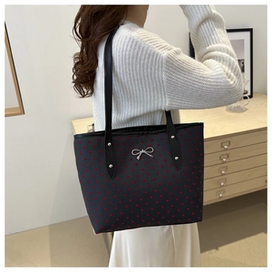 Détail du sac cabas montrant les motifs de cœurs rouges et le nœud argenté sur tissu