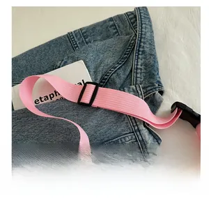 Détail de la bandoulière tissée rose réglable avec boucles en plastique sur un sac bandoulière