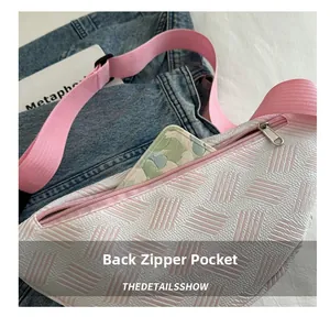 Détail de la poche zippée arrière sur un sac bandoulière blanc avec sangle rose tissée