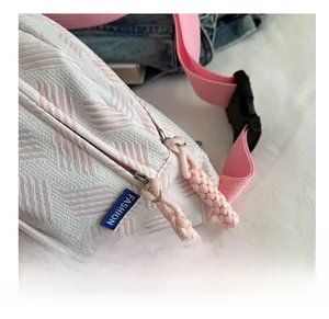 Gros plan sur les doubles fermetures éclair en métal avec tirettes roses sur un sac rayé