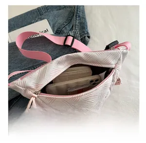 Sac banane rayé rose et blanc montrant l'intérieur spacieux avec smartphone et portefeuille