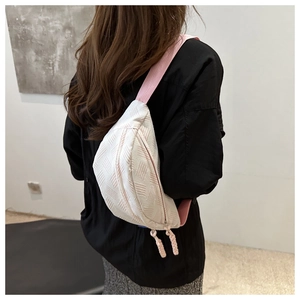 Détail du sac de poitrine blanc texturé avec sangle rose et tirettes de fermeture éclair