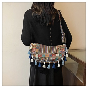 Detail of bohemian woven crescent bag featuring colorful patterns and layered fringe