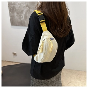 Détail du sac de poitrine blanc texturé avec large bandoulière jaune et étiquette