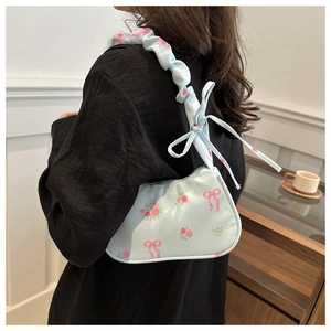Detail of light blue floral hobo bag featuring ruched shoulder strap and ribbon bows