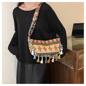 Detail of bohemian crescent bag featuring colorful tassels and ethnic geometric patterns