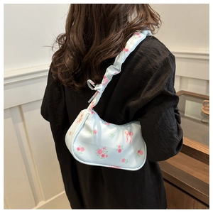 Detailed view of light blue floral shoulder bag with pink roses and bow patterns